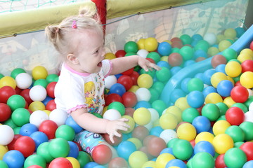 Fototapeta na wymiar Mothers with babies plays in dry swimming pool and sits on the colored plastic balls.