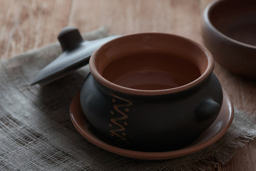 Empty clay baking pot with lid on wooden table.