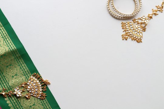 A fragment of colored sari as well as brilliant pendants with bracelets on a white background.