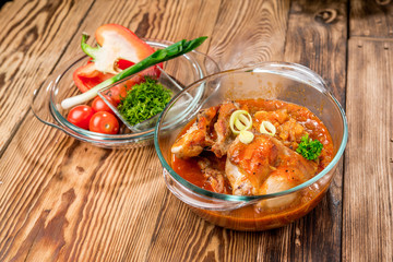 Roasted rabbit with herbs, tomato sauce and glass of wine on a plate.