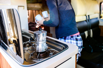 Cooking coffee in campervan, caravan or RV on camping trip.