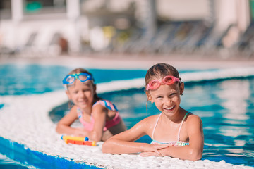 Adorable little girls in outdoor swimming pool
