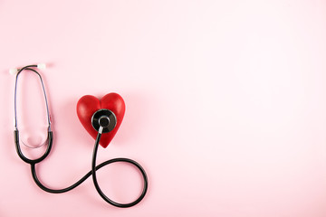 Heart disease awareness and prevention concept. Stethoscope and red heart on pale pink isolated...