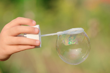 child's hand holding a soap bubble in the ring