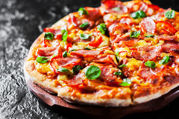 Pizza with Mozzarella cheese, ham, pepper, meat, Tomato sauce, Spices and Fresh Basil. Italian pizza on black background