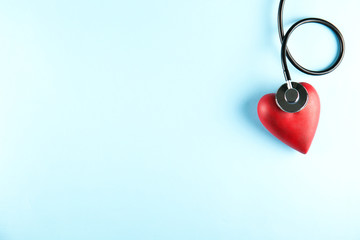 Heart disease awareness and prevention concept. Stethoscope and red heart on pale blue isolated...