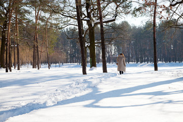 Rear view of woman in warm clothes walking through snowy forest