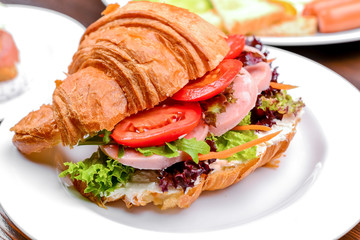 Fresh croissant with ham and salad leaf