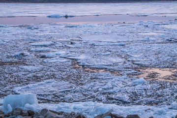 cracked ice on river in spring time during the sunset in pink and lilac colors