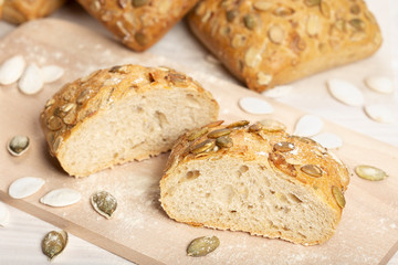 Baked bread with pumpkin seeds on cutting board. Wooden table, rustic style