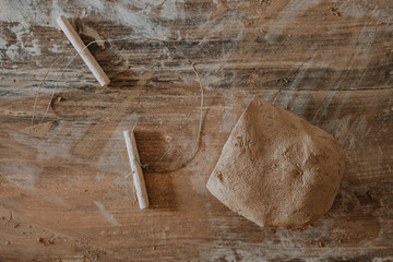 Piece of clay cut with string lying on wooden table prepared for pottery wheel