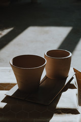 Close-up raw ceramic pottery cup drying on wooden table, clay texture