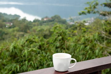 White cup of hot coffee on nature background. Bali island. Volcano Batur.