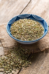 Fennel seeds in a bowl on wood background,