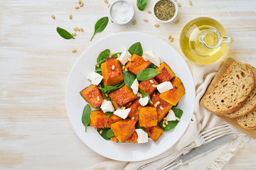 Salad with roasted pumpkin, feta cheese, spinach, nuts with honey and seasonings, top view