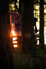 Camping on the beach during the sunset with silhouettes of clothes and towels hanging, tents and forest trees. Picnic and barbecue party outdoors. Concept of relaxation, holidays and recreation