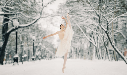 Beautiful ballerina is dancing at walkway of snowy city