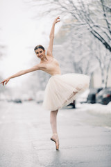 Obraz premium Beautiful ballerina is dancing on street of snowy city.