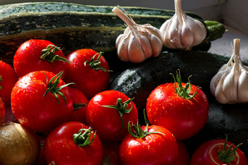 Ripe fresh harvested vegetables on table. Onions, tomatoes, garlic, pepper, zucchini in kitchen. Making delicious vegetarian meal or canning veggies for winter in jars. Concept of healthy eating