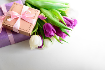 Bouquet of white and purple tulips and gift box on white wooden background. Top view. Flat lay. Copy space. Valentines day, mothers day, birthday, wedding celebration concept.