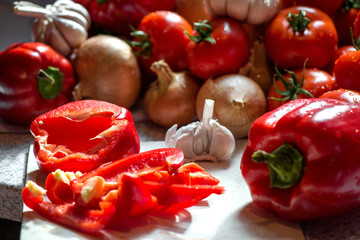 Ripe fresh harvested vegetables on table. Cutting onions, tomatoes, garlic, pepper on wooden board. Making delicious vegetarian meal or canning veggies for winter in jars. Concept of healthy eating