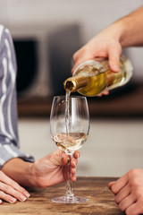 cropped view of of boyfriend pouring wine for girlfriend