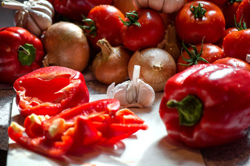 Ripe fresh harvested vegetables on table. Cutting onions, tomatoes, garlic, pepper on wooden board. Making delicious vegetarian meal or canning veggies for winter in jars. Concept of healthy eating
