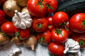 Ripe fresh harvested vegetables on table. Onions, tomatoes, garlic, pepper, zucchini in kitchen. Making delicious vegetarian meal or canning veggies for winter in jars. Concept of healthy eating