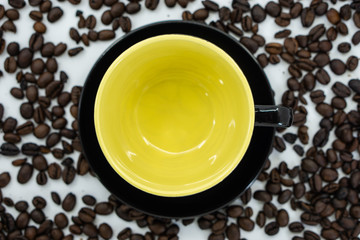 An empty cup with yellow inside on coffee beans background.