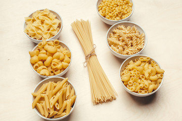 Different pasta types in bowls on the table.