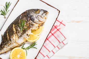 Baked dorado fish with lemon and rosemary top view.