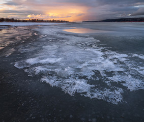sunset is reflected in the river thaw