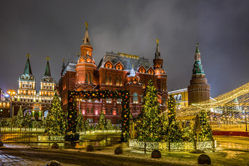 Fototapeta premium Winter night view of the State historical Museum, Iverskaya chapel and Uglovaya Arsenal'naya tower of Kremlin with the Christmas decoration on the Manezhnaya square in Moscow, Russia.