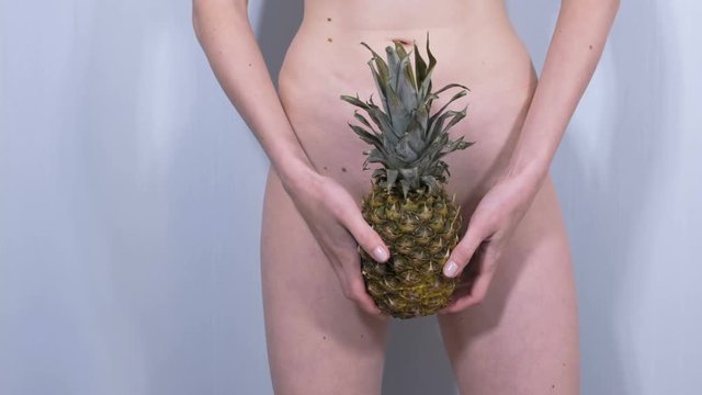 Naked woman's body with pineapple in her hands.