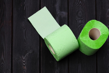 Green toilet paper rolls on black wooden background