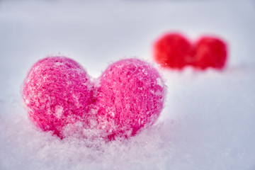 Fototapeta premium Two wool red and pink hearts standing on the white fluffy snow