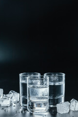 Cold vodka in shot glasses on a black background.
