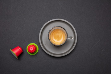 Espresso coffee cup and capsules, pods, on black color background