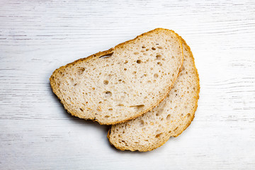 DOS REBANADAS DE PAN RÚSTICO SOBRE FONDO DE MADERA CLARO