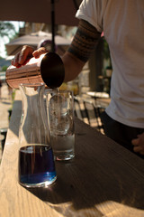  barman pouring a cocktail into a glass with ice