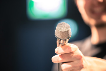 Speaker on the stage: Young Caucasian man is talking into a mirophone