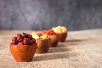 Fototapeta na wymiar Hazelnuts, cashews, Brazil nuts and almond wooden bowls on a gray background.