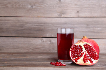 Ripe pomegranates and glass of juice on grey background