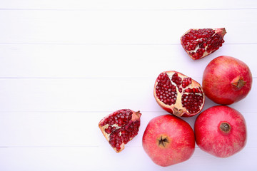 Ripe pomegranates on a white wooden background