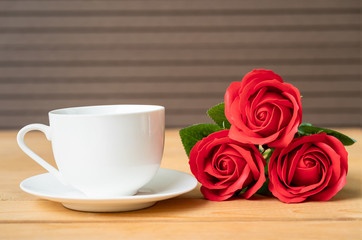 Red rose and coffee cup on wood
