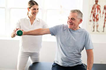 A Modern rehabilitation physiotherapy worker with senior client - obrazy, fototapety, plakaty