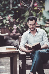 Fototapeta premium man reading a book on a chair in the park, successful people read in the morning every day.