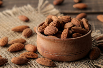almond nut in a wooden bowl close-up on a napkin on a brown wooden table