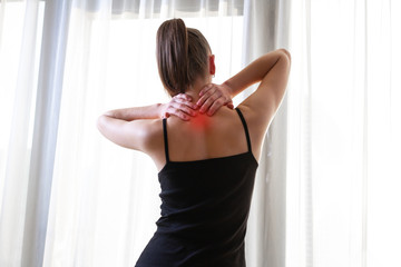 Young woman massaging her neck because of suffering from pain neck, stretching the muscles.