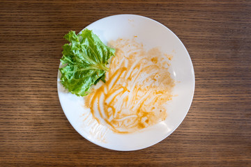 Dirty white dishes on wooden table background. After meal of spaghetti red sauce.